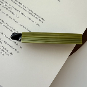 Close-up of green acetate hair clip with stripes on a vintage book backdrop