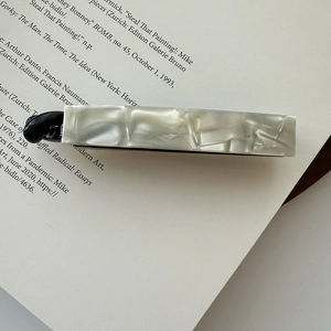 Detail view of acetate hair clip with cream marble texture on a vintage book page