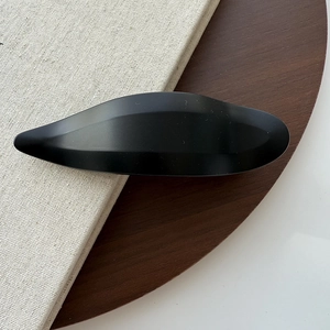 Macro detail of minimalist matte black swallowtail hair clip with geometric leaf design