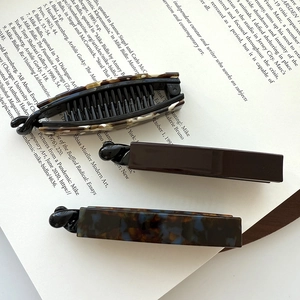 Three acetate banana hair clips with tortoise shell patterns on vintage book pages