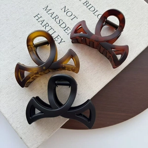 Lot de trois pinces à cheveux nœud en ambre, caramel et noir mat sur un plateau bois