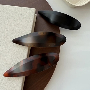 Minimalist acetate hair clips in black and tortoiseshell patterns on a wooden tray