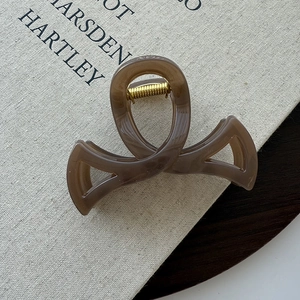 Vue détaillée d'une pince à cheveux en résine ambrée avec ressort métallique doré sur un livre