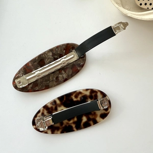 Close-up of tortoise shell and marble acetate hair clips with metal spring mechanism