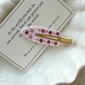 Detail einer lila karierten Haarklammer mit rosa und champagnerfarbenen Strasssteinen