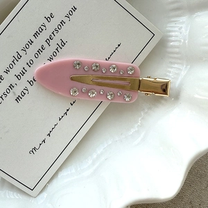 Detail einer rosa Acetat-Haarklammer mit Straßsteinen und Goldbasis auf elegantem Teller