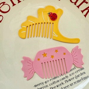 Close-up of cute cartoon acetate combs in ladybug and candy shapes on a ceramic plate