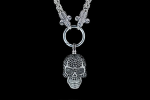 Detail of gothic silver necklace with black zircon skull pendant and ram head links