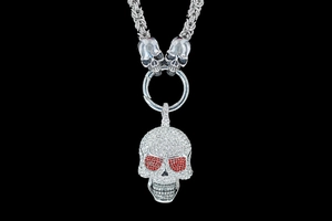 Macro shot of punk skull pendant with white and red crystals on a thick silver chain