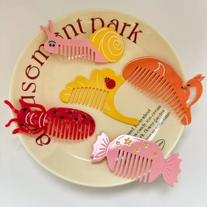 Five colorful animal acetate hair combs featuring snail and fox shapes on a ceramic plate