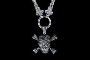 Macro detail of gothic skull pendant with black crystals and ram head link on heavy chain