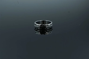 Détail d'une bague punk vintage en acier avec motif de croix et texture martelée robuste