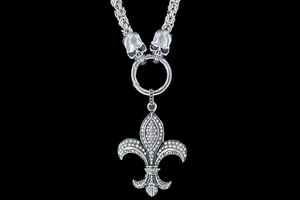 Macro detail of gothic silver necklace with fleur-de-lis pendant and skull links
