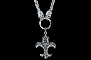 Macro shot of a punk fleur-de-lis pendant with black zircons and silver skull accents