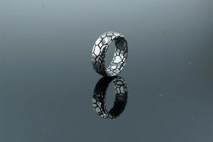 Close-up of silver ring featuring an industrial honeycomb pattern with polished reflection