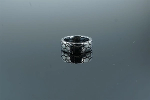 Macro shot of silver textured ring featuring irregular geometric fragments on mirror background