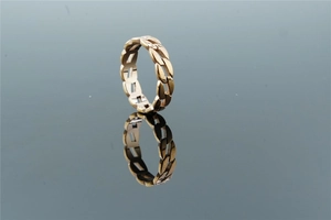 Close-up of golden woven chain link ring showing intricate hollow out metal texture