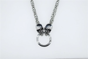 Detailed close-up of punk style double skull pendant with rugged Byzantine chain in silver