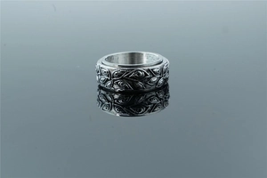 Close-up of vintage spinner ring with embossed leaf patterns on a dark reflective surface