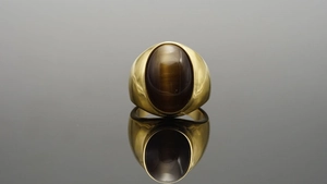 Macro di una pietra occhio di gatto ovale incastonata in un anello vintage in titanio dorato