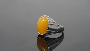 Makro-Seitenansicht eines großen ovalen Bernsteins in einem gestuften Edelstahlring