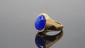 Detalle de un anillo de sello dorado con una piedra preciosa ovalada azul pulida