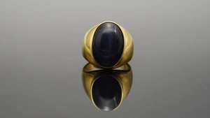 Dettaglio macro di pietra occhio di gatto blu ovale su un anello largo in acciaio titanio oro
