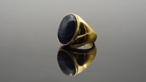 Anello in titanio dorato lucido con una grande gemma ovale scura su specchio nero