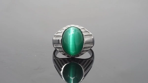 Detail eines silbernen Titanrings mit grünem Katzenaugenstein und geometrischem Band