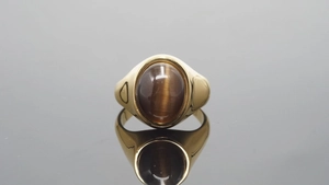 Macro detail van vergulde roestvrijstalen ring met ovale bruine kattenoog edelsteen