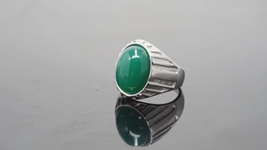 Nahaufnahme eines silbernen Titanrings mit grünem ovalem Stein und geripptem Design