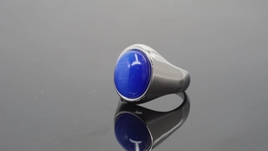 Detalle de un anillo de acero inoxidable plateado con una gran piedra de ojo de tigre azul