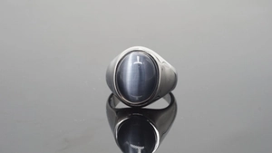 Detailopname van een stalen ring met een grote ovale grijsblauwe edelsteen en kattenoogeffect