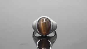 Macro detail van de brede roestvrijstalen herenring met een ovale bruine tijgeroog steen