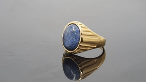 Details eines goldenen Siegelrings mit ovalem blauem Stein und Strukturstreifen