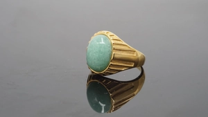 Makro-Detail des Goldrings mit ovalem grünen Edelstein und horizontaler Rillenstruktur