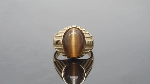 Detailansicht eines goldenen Herrenrings mit braunem Katzenaugen-Edelstein Besatz