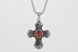 Gros plan du pendentif croix en acier avec oeil maléfique rouge et gravures complexes
