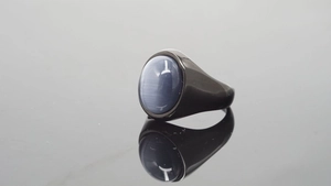 Detalle de una gema ovalada gris azulada engastada en un anillo de acero inoxidable negro
