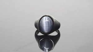 Macro-opname van zwarte roestvrijstalen ring met een ovale grijsblauwe kattenoog