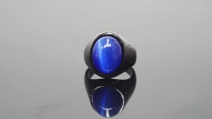 Macro-opname van matzwarte roestvrijstalen ring met ovale blauw-paarse kattenoogsteen