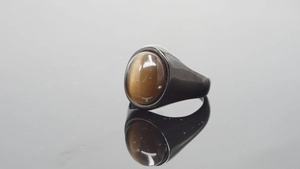 Vista macro de un anillo retro de acero negro con una piedra ojo de tigre ovalada