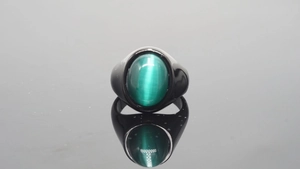 Macro-opname van zwarte vintage ring met groene kattenoogsteen en weerspiegeling