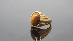 Detailansicht eines ovalen Tigerauge-Edelsteins in einem goldenen Punk-Stahlring