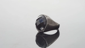 Vista macro de un anillo de sello minimalista de acero negro con una gran piedra redonda
