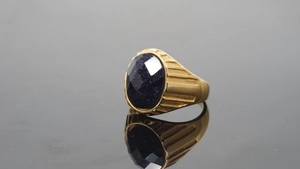 Detailansicht eines Herrenrings mit dunkelblauem Schmuckstein und goldener Textur