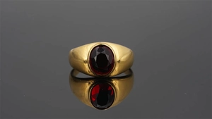 Vista detallada de un anillo vintage bañado en oro con una gema roja de corte oval