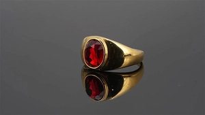 Primer plano de anillo de sello dorado con piedra preciosa roja ovalada y reflejo nítido