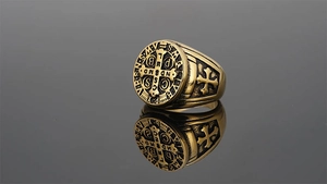 Détail macro d'une bague sceau Saint Benoît dorée avec croix gravée et relief religieux