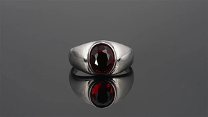 Primer plano de anillo vintage de acero inoxidable con gema roja ovalada y acabado pulido
